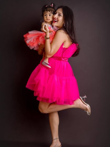 A mother and daughter in matching vibrant dresses, sharing a joyful moment. These playful shots showcase the fun side of their bond.