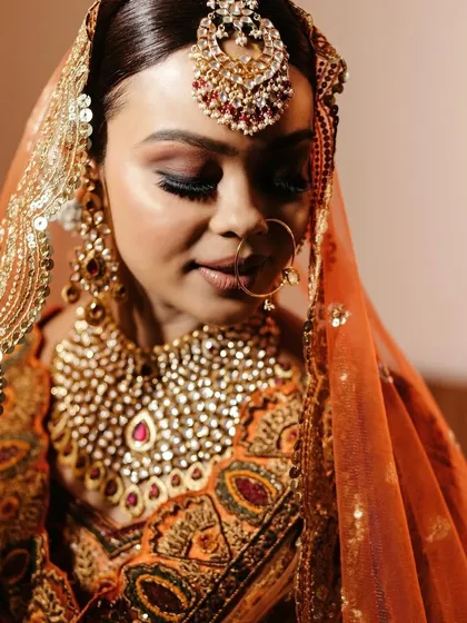 A beautiful close-up of the bride in her rich orange and gold wedding attire, her serene expression capturing a moment of quiet contemplation.