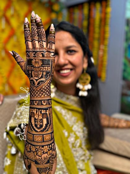 A beautiful shot of a bride displaying her full back hand mehndi. The design is a mix of traditional patterns and figures, creating a rich and textured look that is both elegant and eye catching.