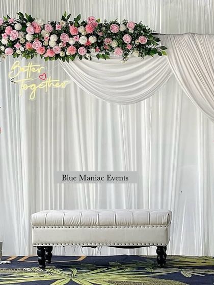 A beautiful example of a pink and white floral theme for an engagement. This setup uses a rectangular frame with an asymmetrical floral arrangement, a 'Better Together' neon sign, and a clean white backdrop for a fresh and modern feel.
