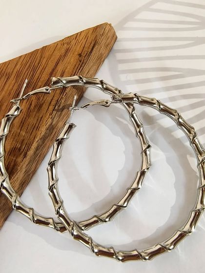 A clean product shot of the twisted metal hoop statement earrings, showcasing their bamboo-like texture.
