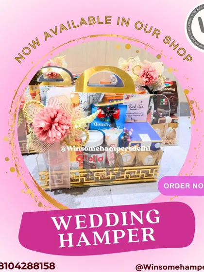 This wedding hamper is ready to order from my shop. The design features a golden acrylic basket filled with treats and adorned with a pink floral arrangement.