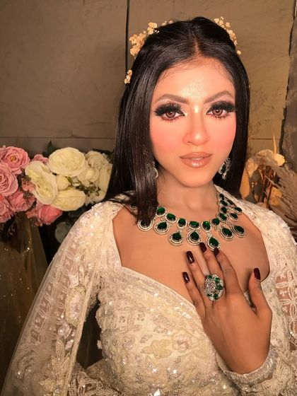 This shot highlights the beautiful emerald ring and the perfectly manicured nails, which complement the overall color scheme of the look.