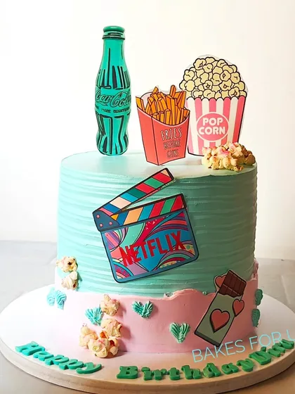 A Netflix and chill-themed cake, perfect for a movie lover's birthday. The design features edible popcorn, fries, and a Coca-Cola bottle, all ready for a binge-watching session.