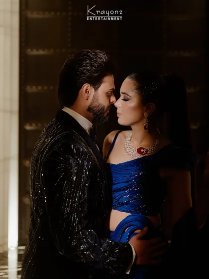An intimate moment between the couple amidst the Sangeet night's excitement. The electric blue of the bride's outfit complements the dazzling stage lights.