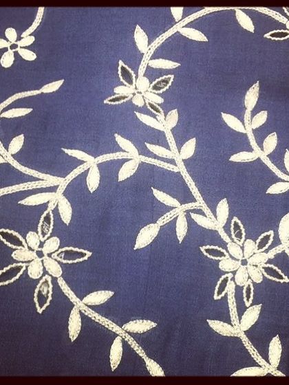 Even simple threadwork can be incredibly elegant. This photo shows a delicate vine pattern created with white and gold thread on a deep blue fabric, perfect for a subtle yet sophisticated design.