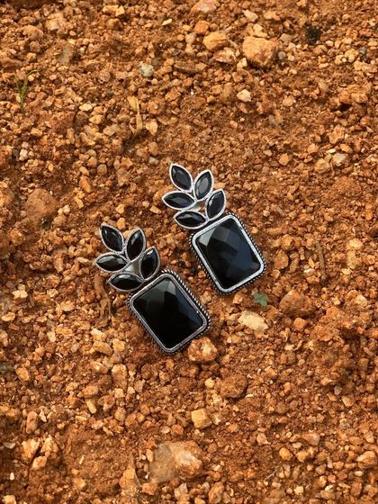 A classic pair of black polish silver replica earrings. The rectangular black stone is framed by a leaf motif, creating a simple yet elegant design.