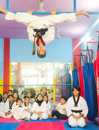 Flexibility is a cornerstone of our training. This student demonstrates incredible control and strength with an upside down split on the bar, a testament to our advanced acrobatics and conditioning program.