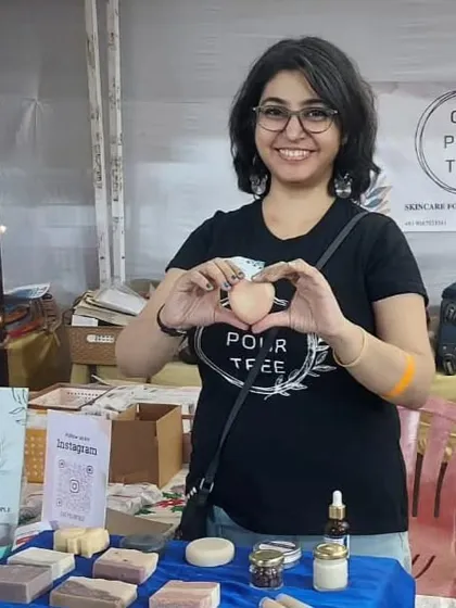 Me holding up a heart-shaped soap at my stall, making a heart with my hands. It's all about spreading the love!