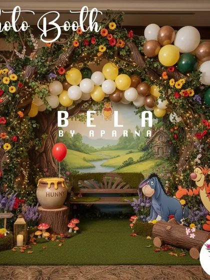 I design dedicated photo booths that continue the party's theme. This one features a rustic wooden bench set against a painted woodland backdrop, framed by a tree-like arch with balloons and character cutouts for memorable photos.