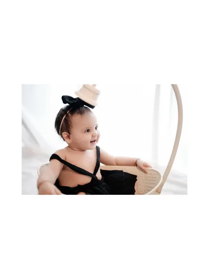 A sweet profile shot of a baby girl sitting in a wicker basket. The soft lighting and her happy expression make this a truly lovely portrait.
