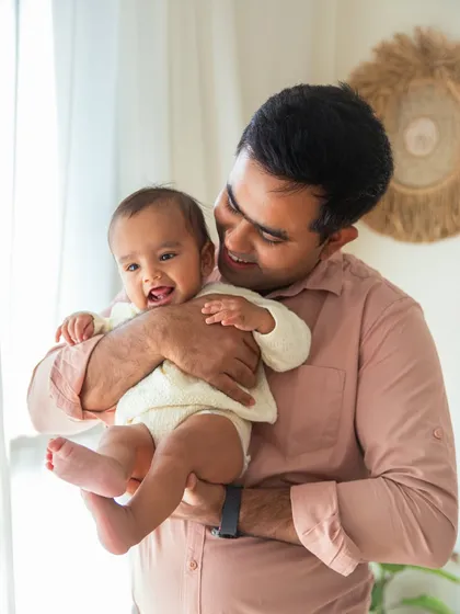 A father's gentle hold and a baby's happy smile. This portrait from a 6-month session perfectly captures the tender bond between a dad and his child.
