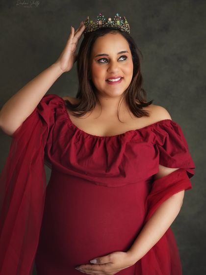 A close-up on the queen. This shot focuses on the mom-to-be's happy expression as she adjusts her crown, radiating confidence and the joy of her pregnancy.