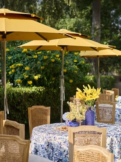 A row of poolside dining tables shaded by yellow umbrellas, creating a chic, resort-like atmosphere for the daytime event.