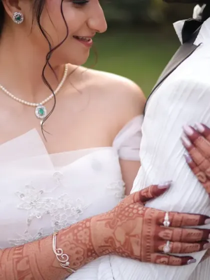 A close-up showcasing the fusion of traditions. The intricate henna on her hands beautifully contrasts with the delicate lace of her white wedding gown, a detail I love to highlight.
