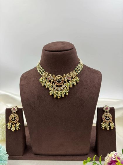 The "Royal Hathi" antique gold necklace set, shown in multiple color variations. This design features elephant motifs and is available with white, red, or multi-color stones, paired with a multi-strand pearl chain.
