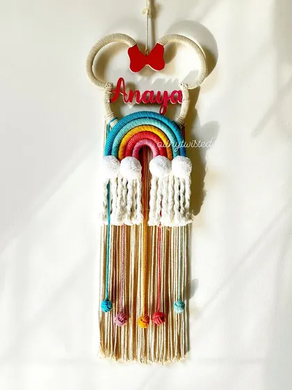 For the little Disney fan, I created this Minnie Mouse-themed nameplate for 'Anaya'. It combines the iconic mouse ears and bow with a colorful macramé rainbow and hanging tassels.