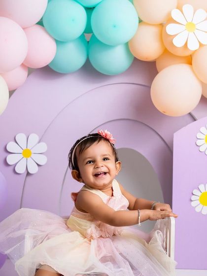 A happy smile before the mess. The pastel rainbow and daisy theme is a beautiful and cheerful choice for a baby girl's first birthday.