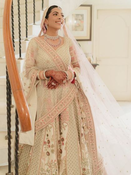 A full length shot of Nidhi's stunning pastel bridal look. The makeup is light and airy, perfect for a daytime wedding.