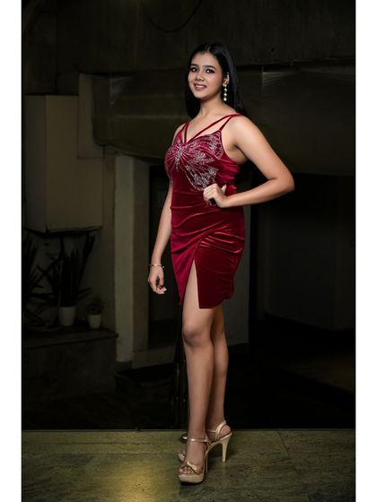 A three-quarter shot perfect for a commercial or fashion portfolio. The model's pose is confident and engaging, and the lighting clearly shows the details of the embellished red dress.