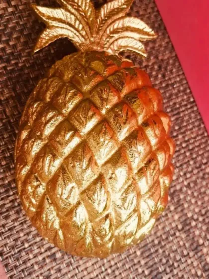 A close-up of the textured, golden pineapple urli candle lid.