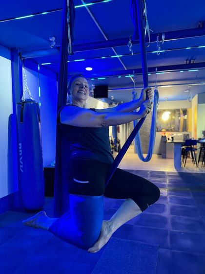 A member poses with the hammock, showcasing a moment of strength and poise during a personal training session.