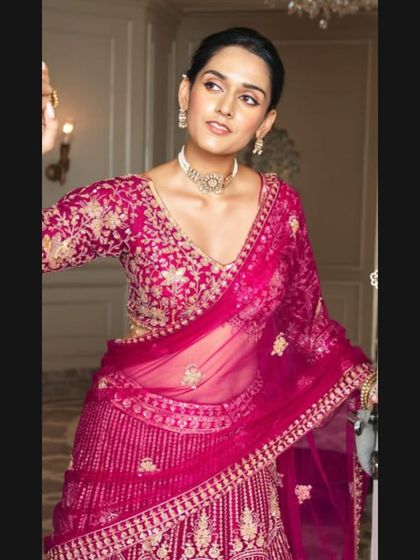 A closer look at the fuchsia pink bridal lehenga, focusing on the detailed embroidery of the blouse and the delicate sheer dupatta.