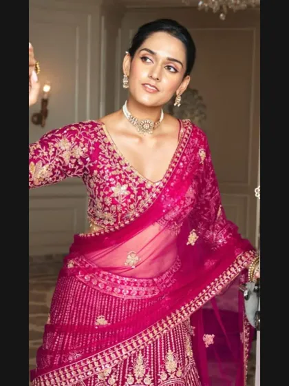 A closer look at the fuchsia pink bridal lehenga, focusing on the detailed embroidery of the blouse and the delicate sheer dupatta.