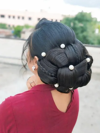 An elegant updo created with intricate weaving and braiding techniques. The style is adorned with pearls, making it a sophisticated choice for any formal event.