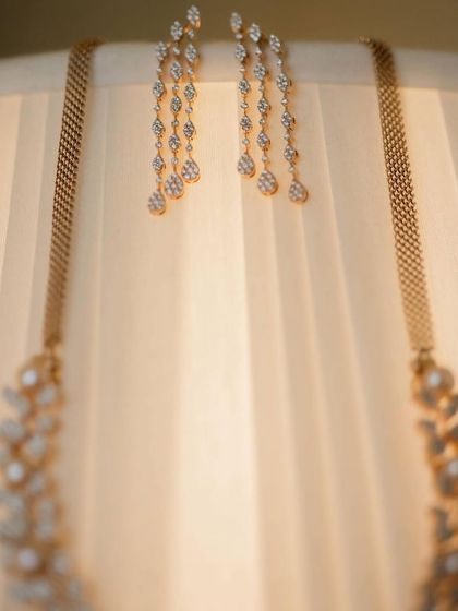 An artistic shot of diamond jewelry hanging from a lampshade, using the light to create a soft and elegant image.