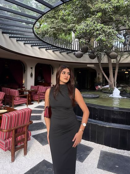"She's the destination." A stunning black maxi dress, shot in a beautiful courtyard with a fountain.