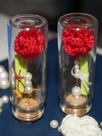 Two red rose 'message in a bottle' gifts, side-by-side. The little pearls and star details add a touch of magic.