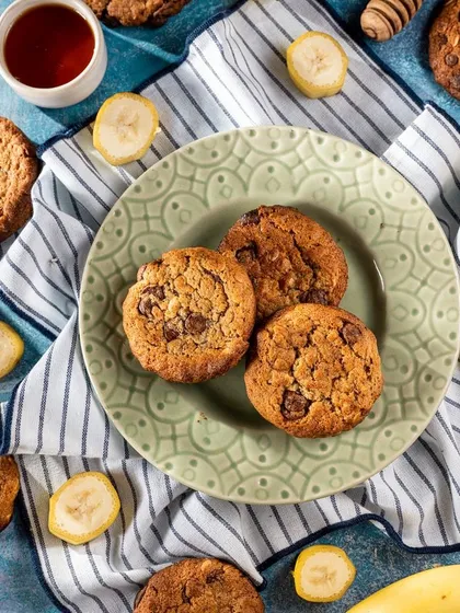 A flatlay of banana chocolate chip cookies with their core ingredients scattered around. This styling approach tells the story of what goes into the cookies, emphasizing their fresh, homemade quality.
