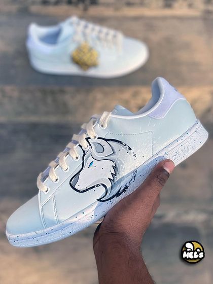 A hand-held shot of the white wolf side of the custom Adidas Stan Smiths.