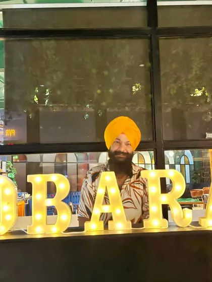 Posing behind the "DOBARAA" sign at a gig. My job is handling vibes with a smile and keeping everyone busy on the dance floor.