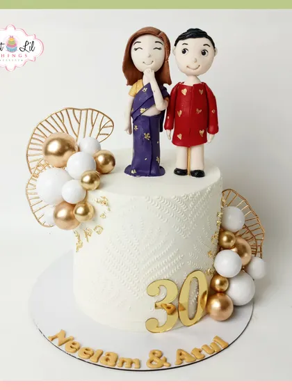 Celebrating 30 years of love with this elegant anniversary cake. It features custom fondant toppers of the couple in traditional attire, surrounded by white and gold spheres.