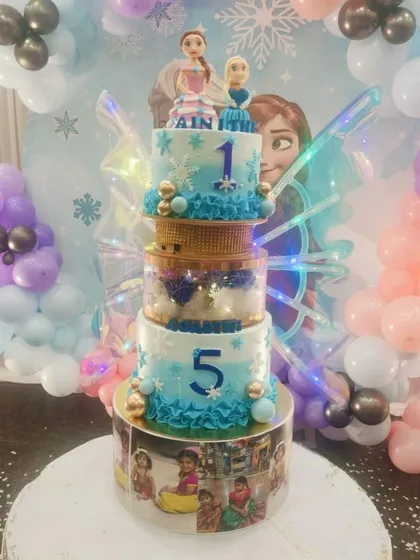 A spectacular multi-tiered cake with a Frozen theme, complete with Anna and Elsa toppers and light-up butterfly wings. The bottom tier can be customized with your child's photos for a personal touch.