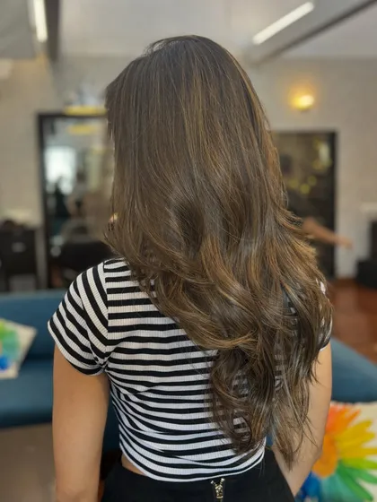 A back view of this stunning balayage, showing how the light caramel tones are blended seamlessly into her natural brown base for a soft, dimensional look.