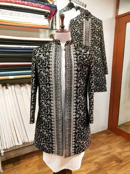 This is a showcase of our traditional craftsmanship. A black and silver embroidered sherwani, designed for a groom, displayed on a mannequin to highlight the detailed brocade work and elegant silhouette. This piece is perfect for a grand wedding ceremony.