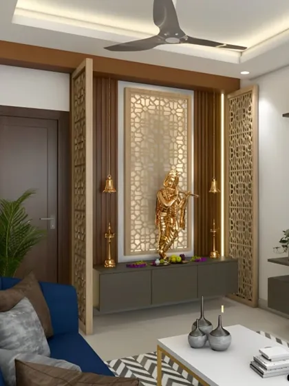 This pooja unit is seamlessly integrated into a living room, using decorative jaali screens as partitions. This approach defines the sacred space without closing it off, maintaining an open and airy feel. The design combines traditional patterns with a modern color palette, ensuring it complements the overall home decor.