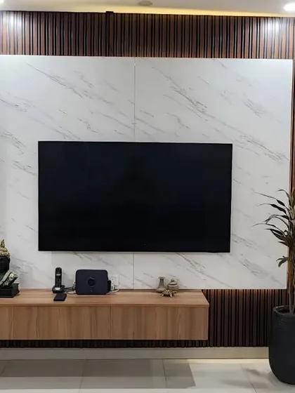 This sleek TV panel is the star of the show in this living room I designed in Greater Noida. I used a combination of satin finish, stone finish laminates, and charcoal paneling to create a stunning, textured focal point.