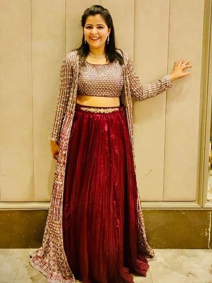 A modern and chic rental option. This outfit features a maroon pleated skirt paired with a heavily embellished long jacket, perfect for a cocktail or reception night.