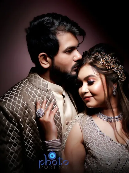 An intimate indoor portrait from an engagement shoot, using moody, directional lighting to create a dramatic and elegant feel. The focus is on the couple's connection, highlighted by the soft light and dark background.