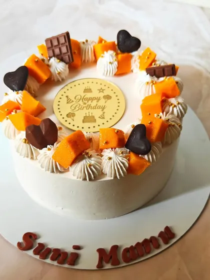 A birthday cake celebrating the mango season. This one is decorated with fresh mango cubes, piped cream, and little chocolate hearts for a festive touch.