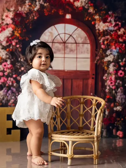 Taking her first proud steps. We love documenting these incredible milestones, like standing on her own, against a beautiful floral backdrop for her first birthday.