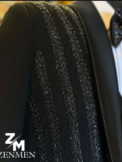A detailed shot of the shoulder and sleeve of the striped tuxedo, showing the intricate leaf-like pattern of the beadwork.