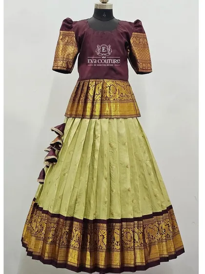 A unique Kanchi Pattu lehenga with a peplum blouse made from the border fabric. The light green skirt has a rich wine-colored border.
