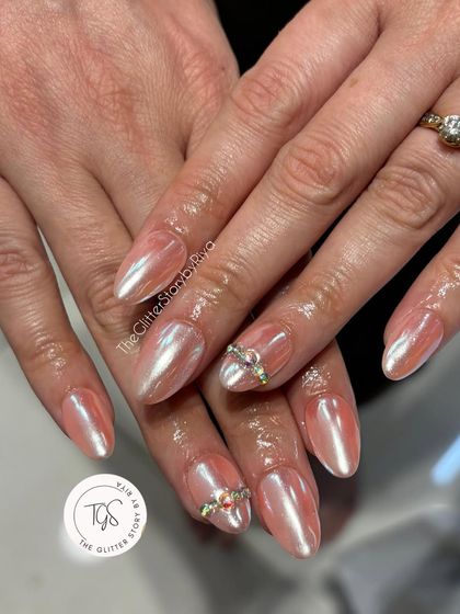 A soft and ethereal chrome nail set. These almond-shaped nails have a beautiful pearlescent pink chrome finish, with delicate crystal bands on the accent nails.