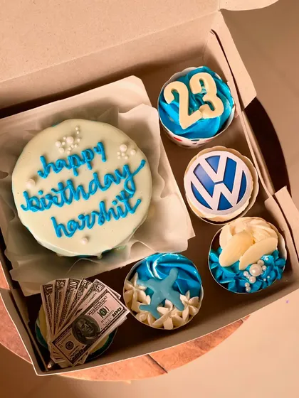 A detailed look at the custom blue-themed birthday hamper. The cupcakes are decorated with the number 23, a car logo, and ocean-inspired designs.