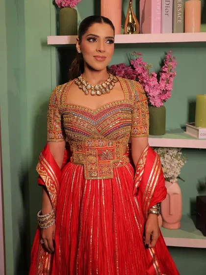 A vibrant and colorful look in a red Abu Jani Sandeep Khosla outfit. The makeup is clean and defined, with a sleek ponytail to keep the focus on the intricate blouse.